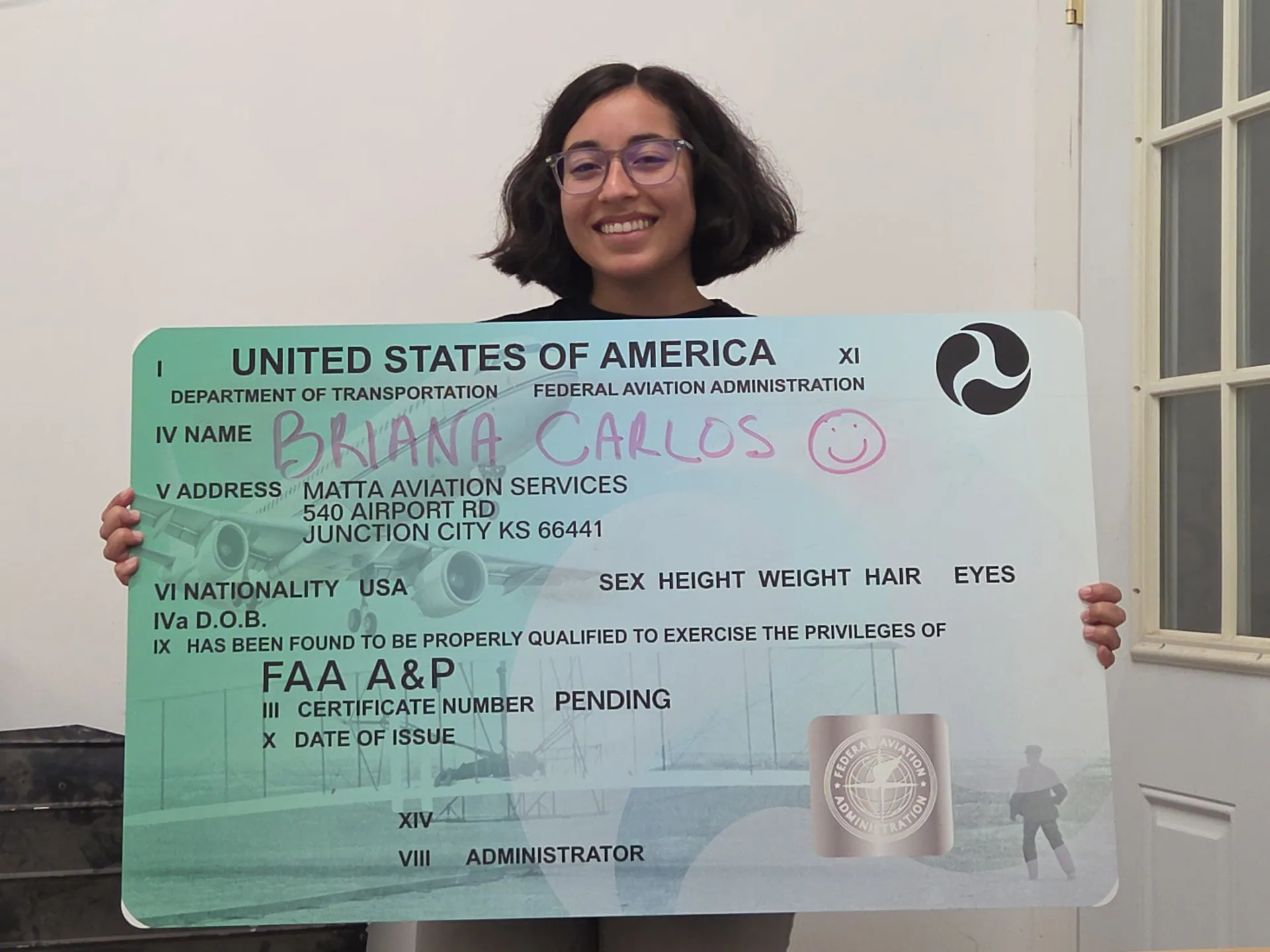 Student holding an FAA Form 8610-2 style certificate